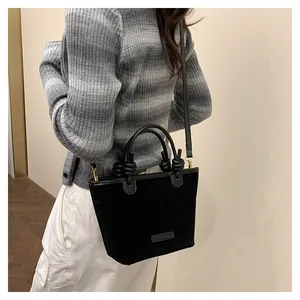 Detailed view of black suede bucket bag featuring leather knot decor and golden metal rings