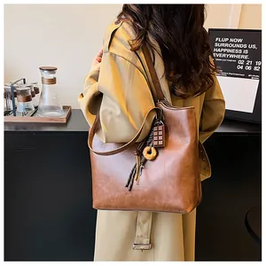 Dettaglio della borsa tote marrone vintage con ciondoli a forma di cioccolato su trench kaki