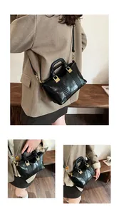Detail of glossy crocodile pattern texture and gold hardware on black crossbody bag
