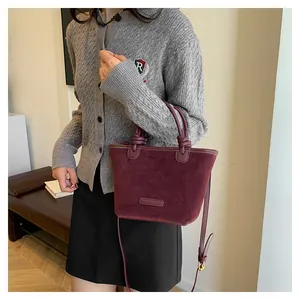 Detail view of retro burgundy suede bucket bag with adjustable strap and knot handle
