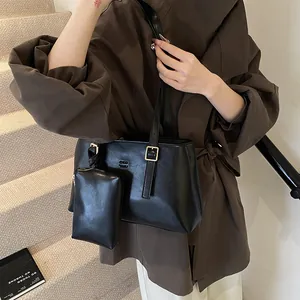 Matte black leather tote bag with matching pouch shown on a model in a lifestyle setting