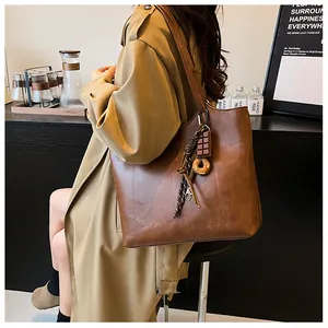 Dettaglio della grande borsa tote marrone vintage con ciondolo donut e morbida pelle PU
