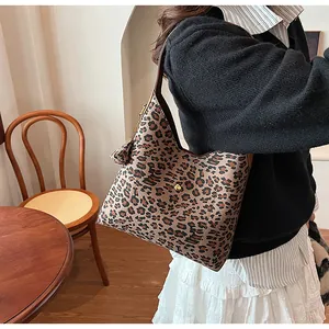 Detail of leopard print underarm bag featuring fringe tassel and brown shoulder strap
