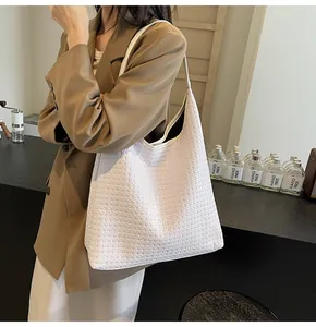 Détail d'un grand sac hobo tissé blanc crème associé à un blazer chic et un pantalon large