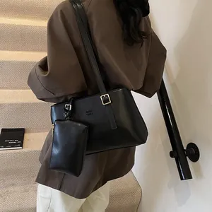 Classic black leather tote bag with gold hardware and matching pouch shown on model