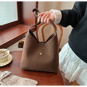 Detail of dark brown faux suede tote bag featuring a gold metal clasp and mini coin purse