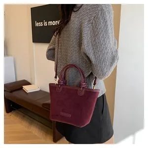 Detail of burgundy suede tote bag with knotted handles and long adjustable shoulder strap