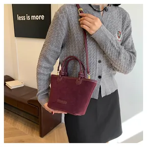 Detail of burgundy suede tote bag featuring leather handles and knotted strap accents