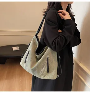Detail of olive green large textured fabric hobo bag with fringe zippers and black strap