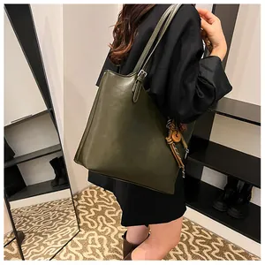 Dettaglio della borsa tote verde oliva con tracolla regolabile e ciondolo intrecciato