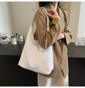 Détail de la texture en cuir tressé blanc d'un grand sac cabas porté à l'épaule