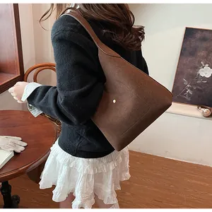 Detail of deep brown suede tote bag with elegant gold buckle and seamless strap design