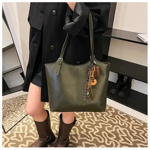 Dettaglio di una grande borsa tote verde oliva in pelle PU con ciondoli decorativi