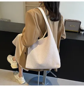 Détail de la texture tressée blanche d'un grand sac cabas porté à l'épaule