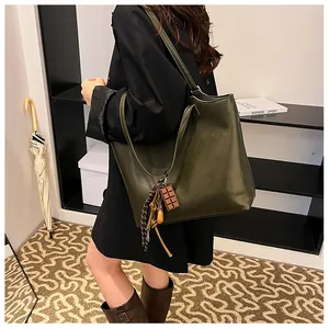 Borsa tote in pelle PU verde oliva scuro indossata a spalla con charm di cioccolato