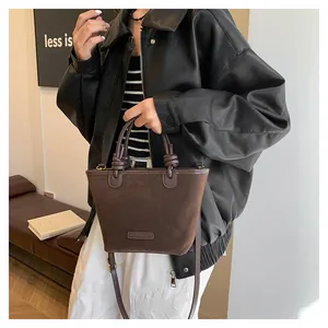 Close-up of dark brown suede bucket bag with unique knotted handle and vintage hardware