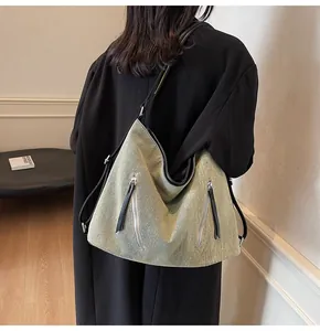 Detail view of large sage green tote bag with diagonal zippers on model back