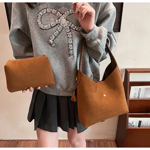 Close-up of brown suede hobo bag set with tassel detail and matching zipper pouch
