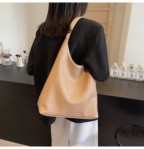 Détail de la texture du grand sac cabas tissé et de la large bandoulière sur un modèle