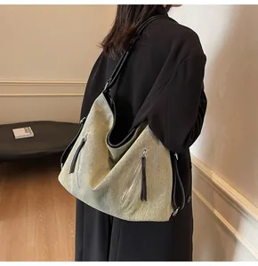 Detail of light green canvas hobo bag with black leather straps and zipper accents