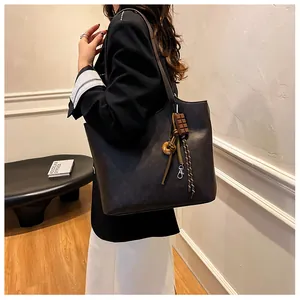 Dettaglio della borsa tote marrone scuro con texture pelle e ciondolo a ciambella creativo