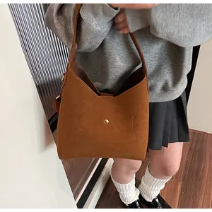 Brown suede tote bag with golden metal buckle decoration on an adjustable shoulder strap