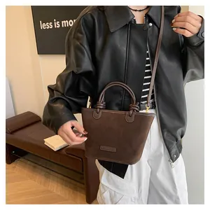 Detailed look at brown suede crossbody bucket bag styled with a leather jacket