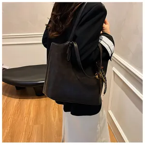 Dettaglio della borsa tote in pelle marrone scuro con nappa decorativa e doppi manici