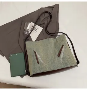 Detailed view of washed denim tote with brown leather trim and dual silver zippers