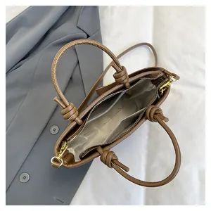 Top view of brown faux leather bucket bag with knot handles and golden zipper detail