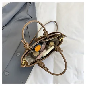Detail view of coffee brown leather bucket bag interior and stylish knotted handle design