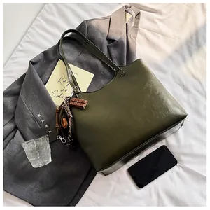 Dettaglio della borsa tote retrò verde oliva con ciondolo al cioccolato su abito grigio