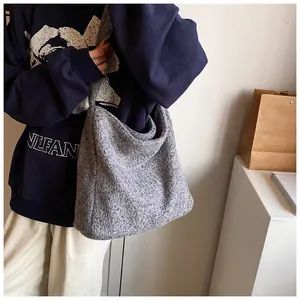 Detailopname van de grote grijze tweed tote tas met een brede geïntegreerde schouderriem