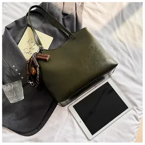 Dettaglio borsa tote in pelle verde scuro con ciondolo a cioccolato su sfondo neutro