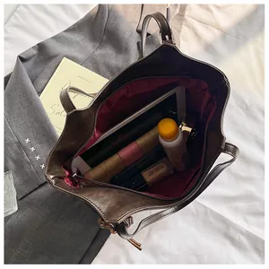 Vista interna della borsa tote marrone con fodera rossa, tasca con zip e ampia capienza