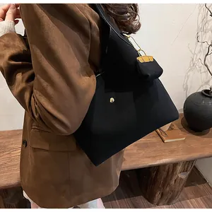 Detail of black minimalist shoulder tote bag with gold stud and matching mini pouch