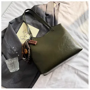 Dettaglio della borsa tote verde oliva scuro con ciondolo a cioccolato e accessori
