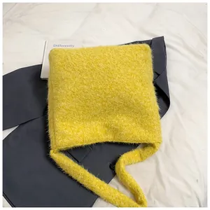 Dettaglio di una borsa tote in ecopelliccia giallo limone su un blazer grigio invernale