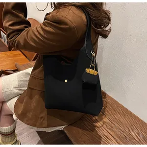 Close-up of black suede underarm bag with gold buckle and a mini bag charm accessory