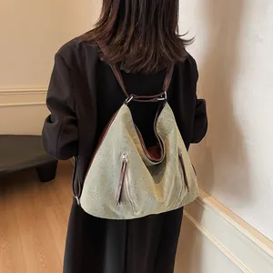 Versatile grey-green canvas hobo backpack with brown leather trim and metal zippers