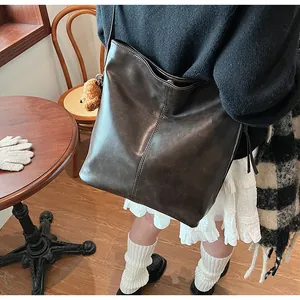Détail du sac cabas vintage en cuir ciré marron foncé avec un charmant ours en peluche