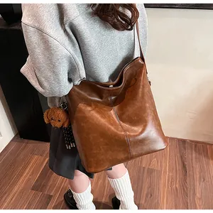 Détail d'un grand sac vintage marron avec couture verticale et breloque chien peluche