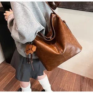 Détail d'un grand sac cabas en cuir marron rétro avec charmant ours en peluche doux