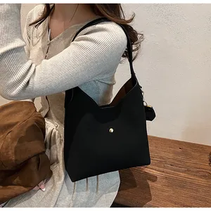 Side view of a black matte leather hobo bag with a golden buckle on a model shoulder
