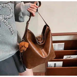 Détail du sac cabas vintage en cuir marron avec breloque ours et large bandoulière