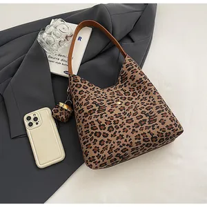 Detail of leopard print hobo bag with brown leather handle and mini pendant