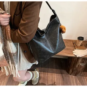 Détail d'un grand sac cabas vintage noir avec coutures verticales et pompon décoratif