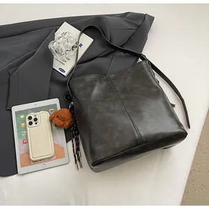 Vue détaillée d'un grand sac seau gris vintage en cuir avec un joli grigri en peluche