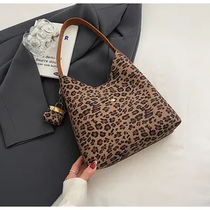Detail of leopard print tote bag with brown leather strap and gold snap button closure