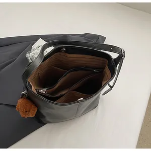 Vue intérieure du sac seau noir avec doublure rayée, poches et charm ours en peluche